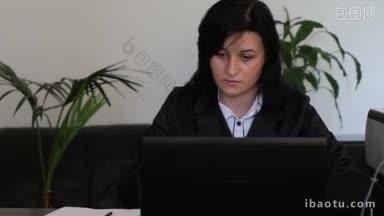 年轻的女商人在她的办公室里用笔记本电脑工作